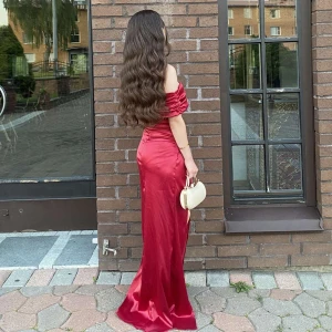 Röd offshoulder långklänning med slits - Snygg röd långklänning i glansigt material med offshoulder och draperade ärmar. Klänningen har en hög slits framtill som ger en extra touch och markerar figuren på ett elegant sätt. Perfekt för dig som vill sticka ut med en glamorös look. Har bara använts en gång och är i nytt skick då den inte har några skador alls! Storlek:XS! den är köpt från shein men har en utmärk kvalité!