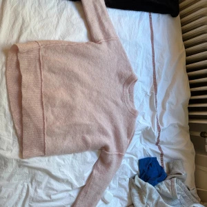 Ljusrosa stickad tröja By Malene Birger - Supermjuk och fluffig ljusrosa stickad tröja från By Malene Birger. Klassisk rund halsringning, ribbade muddar och lång ärm. Perfekt för lager-på-lager och chill vibes. Enkel och stilren design som är lätt att matcha.