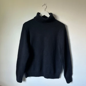 Mörkblå polotröja från Superdry - Klassisk mörkblå polotröja från Superdry Studios med ribbad krage, ärmslut och nederkant. Tröjan är i en mjuk blandning av ull, nylon och polyester och har en clean, stilren look som funkar till allt. Perfekt för kyliga dagar och enkel att matcha med jeans eller byxor. 3V10