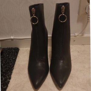 Even&Odd Ankelstövletter  Storlek 37 - Eleganta svarta ankelstövletter från Even&Odd. Stövlarna har en spetsig tå och en smal klack ungefär 3 tum. Detalj med dragkedja framtill med en dekorativ ring. Skorna är väldigt lätta och bekväma. Passar bra till utsvängda jeans/byxor (ingen skokartong) 