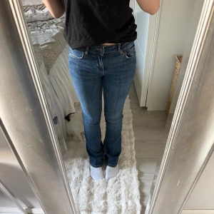 Blå bootcut jeans med låg midja - Säljer ett par klassiska blå jeans med bootcut-modell och låg midja. Jeansen har en snygg tvätt, raka ben som blir lite utsvängda nertill och stora bakfickor. Perfekta till sneakers eller boots och passar dig som gillar en tidlös look.