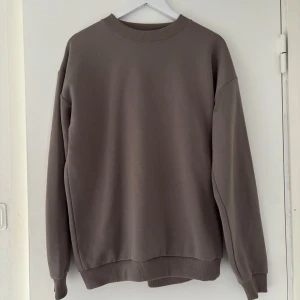 Brun oversized sweatshirt - Enkel och stilren brun sweatshirt med rund hals och långa ärmar. Oversized passform med ribbade muddar vid ärmslut och nederkant. Perfekt för en avslappnad look.