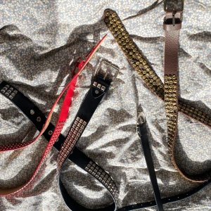 Blandade bälten - Fyra bälten med coola nitar och detaljer: ett svart bälte med silverfärgade fyrkantiga nitar (99cm), ett rött bälte med små runda nitar (107cm), ett brunt bälte (108cm) med stora guldfärgade nitar och ett smalt svart bälte (99cm) med silverdetalj vid spetsen. Perfekt för att ge outfiten en edgy vibe. Kom med prisförslag