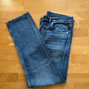 Arket blå jeans 31/32 - Klassiska jeans i blå denim med raka ben och femficksmodell. Jeansen har normal passform och är tillverkade i slitstarkt bomullstyg. Perfekta för dig som gillar tidlös stil och vill ha ett par ikoniska jeans i garderoben. 