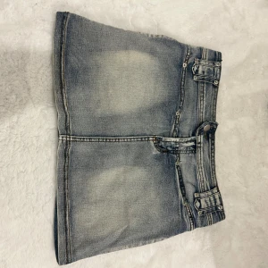 Blå jeanskjol med fickdetaljer - Snygg kort jeanskjol i ljusblå tvätt med slitningar och coola fickdetaljer bak. Aldrig använd då jag inte fick tillfälle för det. Storleken är 10 men skulle säga 38-40