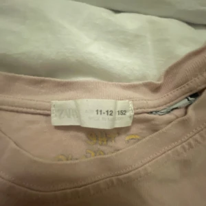 Rosa Bart Simpson t-shirt från Zara - Rosa t-shirt från Zara med tryck av Bart Simpson och texten 'El Barto' på framsidan samt ett stort motiv och citat på baksidan. Skön passform och klassisk rund hals. Perfekt för dig som gillar The Simpsons och vill sticka ut med en cool look.