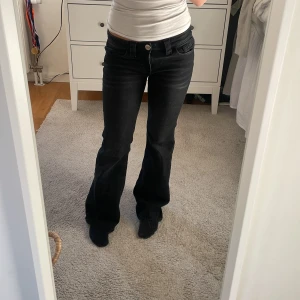 Svarta bootcut jeans från Gina Tricot - Snygga svarta jeans från Gina Tricot i storlek 158. Modellen har bootcut-ben och låg midja, med coola detaljer i form av nitar på bakfickorna. Jeansen är tillverkade i klassiskt denimtyg och har en stilren look som passar till många olika outfits.