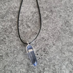 Halsband med blå kristallhänge - Hänge med halsband i läder liknande material samt liten kedjedel. Smyckes storlek: ca 41mm x 13mm  Kedjestorlek: ca 45cm - 50cm Observera att ditt smycke kan skilja sig något från bilderna på grund av naturliga material.🎈Fri frakt❤️