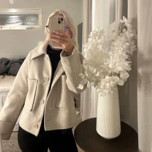 Beige kappa - Säljer en beige jacka från Kappahl i storlek XS. Jackan har stora fickor framtill, klassisk krage och stängs med knappar. Köpt våren 2023 för 900kr men har endast används få gånger! Super fin men är tyvärr tvungen att sälja då jag har alldeles för mycket jackor 🩷