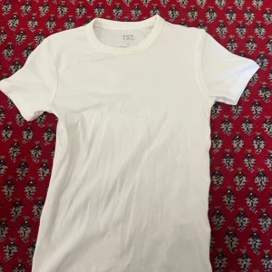 Vit t shirt - Vit t shirt som kan vara bra att ha under andra kläder eller även själv, sminkfläck finns på kragen samt bredvid ena axeln (fotat).  Skönt material och sitter fint på kroppen. Prutning är välkommen.
