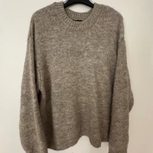 Beige stickad tröja från Ginatricot - Mysig beige stickad tröja från Ginatricot i storlek S. Tröjan har en rund halsringning, ribbade muddar och långärmade ärmar. Perfekt för att hålla sig varm under kyliga dagar och har en loose passform som ger en chill vibe.