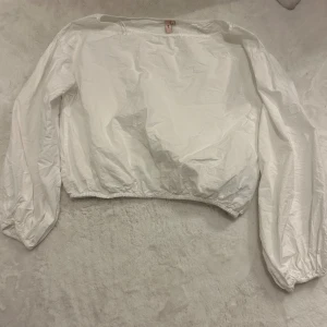 Vit one-shoulder topp med ballongärmar - Jättefin one shoulder topp från Nelly som går in lite i midjan. Säljer den då den inte sitter som jag önskade. Aldrig använd men tvättad så det därför den är lite skrynklig 