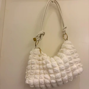 Vit quiltad axelväska med repdetaljer - Superfin vit axelväska med chunky rep som axelrem. Aldrig använd, helt ny utan prislapp.