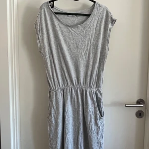 Grå kortärmad klänning  - Enkel och skön grå klänning från lager 157 med korta ärmar. Klänningen har fickor i sidorna. 