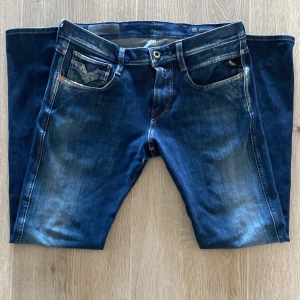 Replay Hyperflex blå jeans - Snygga blå Replay Hyperflex jeans med klassisk femficksdesign och coola slitningar. Jeansen har raka ben, normal passform och är tillverkade i stretchigt denim för extra komfort. Perfekta för dig som gillar en avslappnad men stilren look.