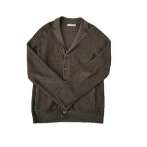 Brun stickad kofta från Dressmann - Mörkbrun stickad kofta från Dressmann med klassisk krage, knäppning framtill och två stora fickor. Koftan har ribbad struktur och långa ärmar, perfekt för lager-på-lager under kyliga dagar.