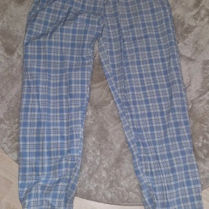 3-pack rutiga byxor från 157, M - Tre par rutiga byxor från 157 i storlek M. Två par är blå- och vitrutiga, ett par är beige - och vitrutiga. Alla har avslappnad passform och resår i midjan, perfekta för chill dagar. Tillverkade i mjukt bomullstyg för extra komfort.