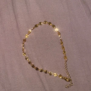 Guldigt armband med blommönster - Snyggt armband i guldton med små blommiga länkar som ger en glittrig och elegant vibe. Justerbar kedja för perfekt passform runt handleden. Perfekt för dig som gillar detaljer och vill ha något som sticker ut lite extra. I rostfritt stål