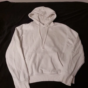 Bershka hoodie relaxed fit - Klassisk vit hoodie med huva och dragsnören. Tröjan har en stor magficka framtill och ribbade muddar vid ärmslut och nederkant. Perfekt för en chill och avslappnad stil. Passar lika bra till jeans som till mjukisbyxor.