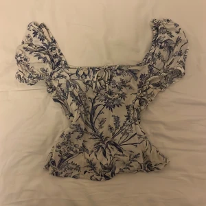 Blommig blus💙🤍 - Säljer en väldigt söt vit blus med blåa blommor på. Den säljs inte längre på hm. Använd några gånger och har en liten sminkfläck (se bild) men märks inte av så mycket. 💙