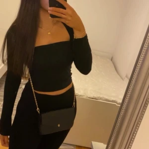 Mörkblå croppad långärmad tubtopp - Säljer en mörkblå croppad tubtopp med långa ärmar och fyrkantig urringning. Toppen är tight och sitter snyggt mot kroppen, perfekt att styla med både jeans och kjol. Gjord i mjukt stretchigt material för en bekväm känsla.