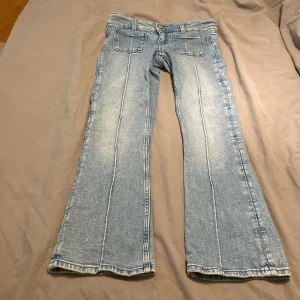 Bootcut jeans från Gina Tricot ljusblå low rised - Snygga ljusblå bootcut jeans från Gina Tricot i storlek 146. Jeansen har framfickor med markerade sömmar, klassisk knappstängning och är tillverkade i mjukt denimtyg. Perfekt för dig som gillar retrovibbar och bekväm passform.