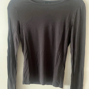 Svart långärmad tröja Gina Tricot - En enkel och stilren svart långärmad tröja från Gina Tricot. Tröjan har rund halsringning och är tillverkad i mjuk bomull, perfekt att matcha med jeans eller kjol. Snygg baströja för alla tillfällen.