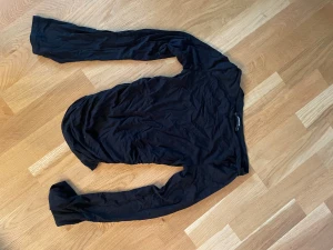 Svart långärmad topp från Gina Tricot - Svart långärmad topp från Gina Tricot i storlek XS. Tunn och mjuk bomullskvalitet som sitter tight och framhäver siluetten. Perfekt att styla med jeans eller kjol.