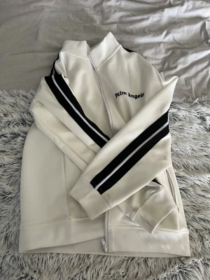 Vit Palm Angels zip up hoodie  - Säljer min fina Palm angels zip up då jag inte gillar den, den är endast använd ett fåtal gånger och är i ny skick. Priset är ej hugget i sten och tveka inte på att höra av dig vid minsta fråga eller funderingar. Mvh