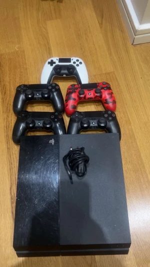 PlayStation 4 med 5 kontroller - PlayStation 4 med fem handkontroller (fyra DualShock 4, en tredjepartskontroll). Konsolen har synliga repor på ovansidan men är fullt fungerande. Perfekt för multiplayer och familjespel. Strömkabel medföljer.