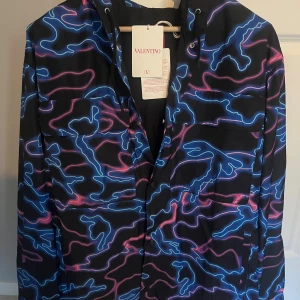 Valentino neonmönstrad vindjacka (kom gärna med bud) - En Valentino jacka som passar perfekt till hösten. Då jag fått den som present så saknar jag kvitto. Har däremot lapparna kvar och en fungerande nfc på insidan. Har även ett äkthetsbevis från Tradera där jag också säljer den. Nypris ligger på runt 20 000. Säljer den pga fel storlek. Den är endast testad en gång och i helt felfritt skick. Storlek 52/ ungefär L. Hör gärna av dig vid funderingar. 