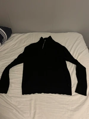 Svart half zip stickad tröja Jack & Jones - Svart stickad tröja från Jack & Jones i storlek M. Tröjan har en snygg half zip-dragkedja vid halsen och långärmad design. 