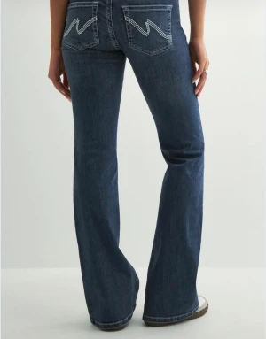 Blå bootcut jeans med broderade fickor - Snygga blå jeans från Nelly med bootcut passform och låg midja. Baktill har fickorna ett coolt vitt broderat mönster. Jeansen har råa, fransiga kanter längst ner och klassiska detaljer som dubbla knappar och fickor fram. Perfekta för dig som gillar en avslappnad stil!!❤️(uppsprättade där nere)