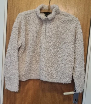 Beige fleece-tröja med half zip - Supermjuk och fluffig beige fleece-tröja från H&M med halv dragkedja framtill. Perfekt för kyliga dagar, har långärmad design och hög krage som håller dig varm. Enkel att matcha med jeans eller mjukisbyxor.