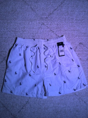 Ralph Lauren badbyxor - Säljer dessa snygga badbyxorna från Ralph Lauren i vitt för bara 249. Brallorna har en snygg och unik design. Hann aldrig använda dessa så att de har bara legat i garderoben . Hoodien är i storlek XL men sitter mer som M, passar mig perfekt som är 178 ish.  Den är redo att hitta ett nytt hem! Fråga gärna om ni vill ha fler bilder eller mer information