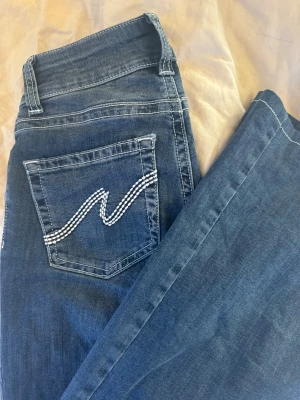 Low waist bootcut stitch jeans - UPPSYDDA/KORTADE! Väldigt fina lågmidjade nelly jeans. Både använda och tvättade endast 1 gång. De är kortade och sydda med ny vit tråd, passar perfekt till dig som är 155-160cm. De va annars va alldeles för långa för mig som är 158cm. De är i väldigt bra skick. Köpta för 699kr