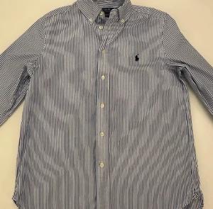 Blårandig skjorta från Polo Ralph Lauren - Snygg blårandig skjorta från Polo Ralph Lauren i slim fit-modell. Skjortan har klassisk krage, knappar framtill och det ikoniska broderade polospelaren på bröstet. Tillverkad i mjuk bomull som känns skön mot huden. Perfekt för dig som gillar stilrena och tidlösa plagg. Pris kan diskuteras!
