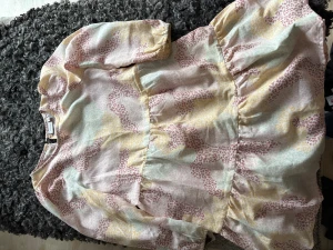 Pastellfärgad leopardklänning Name It - Söt klänning från Name It med pastellfärgat leopardmönster i rosa, gul och turkos. Klänningen har puffiga långärmar, rund hals och volangdetaljer i kjolen. Tillverkad i mjuk polyester som känns skön mot huden. Perfekt för dig som gillar färg och mönster! Lite större i storlek. 