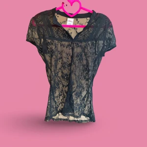 Svart spetsblus från ONLY - Säljer en svart transparent blus från ONLY i storlek L. Blusen har korta ärmar och är helt täckt av ett blommigt spetsmönster. Den har en liten v-ringning och tunna dekorativa band upptill. Perfekt för dig som gillar detaljer och vill sticka ut.