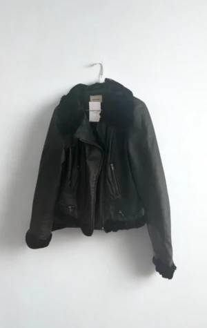 Vintage oversized skinnjacka - Svart skinnjacka med päls på krage, ärmslut och nederkant. Jackan har dragkedja framtill, flera fickor med dragkedja och snygga spänndetaljer bak. Pälsen är lite gles (se bild) Äkta vintage!