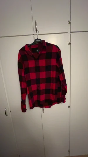 Röd och svart rutig skjorta H&M - Säljer en röd och svart rutig skjorta från H&M i relaxed fit. Skjortan har långa ärmar, klassisk krage och knappar framtill. Perfekt för dig som gillar en chill och avslappnad stil. Materialet är mjukt och bekvämt bomull.