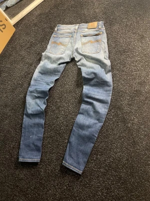 Nudie Jeans blå jeans W28 L32 - Säljer dessa feta nudie jeans, de sitter slimfit och har snygga tvättmärken på knäna. Nypris ligger runt 1700kr vårt pris endast 399.