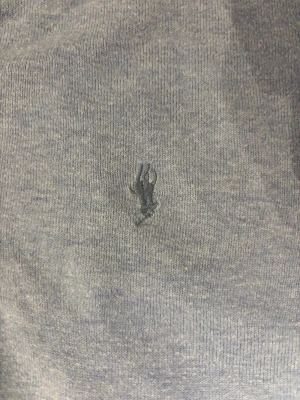 Blå slim fit tröja från Polo Ralph Lauren - Snygg blå tröja från Polo Ralph Lauren i slim fit med klassisk broderad logga på bröstet. Tillverkad i mjuk pima bomull, har långa ärmar och ribbade muddar vid ärmslut och nederkant. Perfekt för dig som gillar stilrena och bekväma plagg.