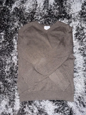 Beige stickad tröja från Bläck - Snygg beige stickad tröja från Bläck med v-ringad hals och ribbade muddar. Perfekt för dig som gillar enkel och stilren design. Långärmad modell som passar till många olika outfits. Materialet är mjukt och skönt mot huden.