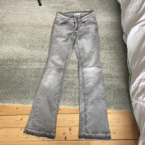 Grå bootcut jeans från Gina Tricot - Säljer ett par gråa bootcut jeans från Gina Tricot, modell Perfect Jeans. Jeansen har en snygg tvättad look, klassiska fem fickor och råa, fransiga benslut. Perfekta för dig som är ca 165 cm❤️