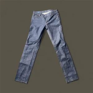 Acne studios jeans i rak modell - Snygga blå jeans från Acne Studios i klassisk rak modell. Jeansen är tillverkade i Italien och har fem fickor, orangea sömmar och en stilren look. Perfekta för dig som gillar enkel och tidlös denimstil.