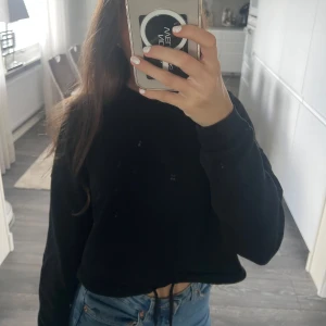 Svart croppad sweatshirt med snörning - Svart croppad sweatshirt med snörning i nederkant. Tröjan har lång ärm och en loose passform som ger en chill vibe. Perfekt att matcha med jeans eller leggings för en avslappnad look. Storlek xxs men passar mig som har xs/s