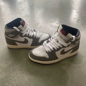 Air Jordan 1 Retro High OG Washed Black - Säljer ett par Air Jordan 1 Retro High OG Washed Black med snygga detaljer i mocka och läder. Skorna har klassisk snörning, svart innersula och röd Nike Air-logga på plösen. Perfekta för dig som gillar streetstyle och vill ha en ikonisk sneaker i garderoben.