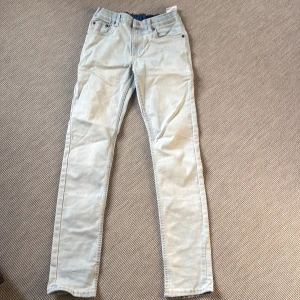 Levi’s 512 - Ljusblå Levi's jeans skinny fit - Ljusblå jeans från Levi's med klassisk femficksdesign och rak passform. Byxorna har normal midja, dragkedja och knapp framtill samt Levi's-logga på bakfickan. Tillverkade i bomull med en mjuk känsla och elastisk midja baktill för extra komfort. Finns några små fläckar på baksidan! 