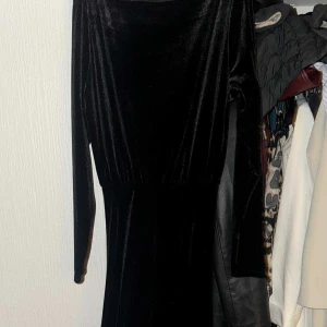 Svart långärmad sammetsklänning - Säljer en svart långklänning i mjuk sammet med långärmade ärmar och markerad midja. Klänningen har en elegant och enkel design som ger en lyxig känsla. Perfekt för dig som gillar klassisk stil med en twist.